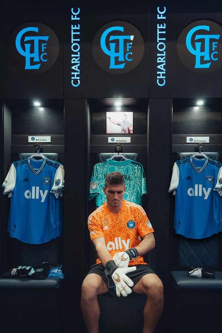 Kristijan Kahlina sits putting on gear in Charlotte FC locker room.