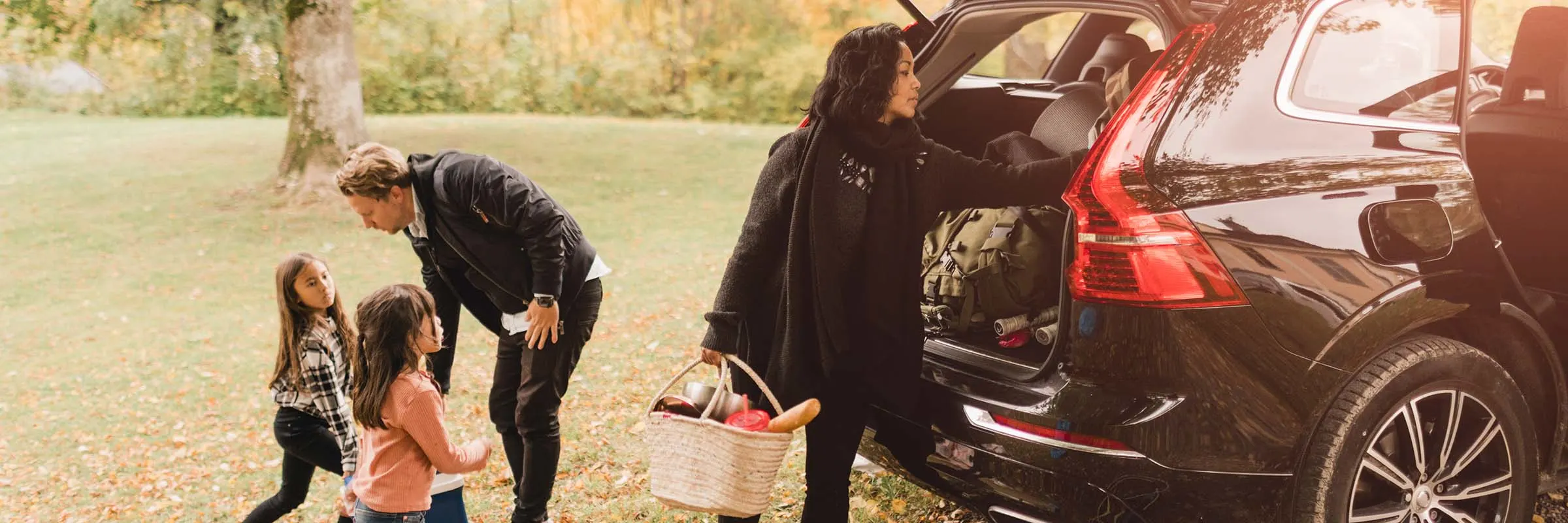 Two children and two adults set up a picnic by an SUV