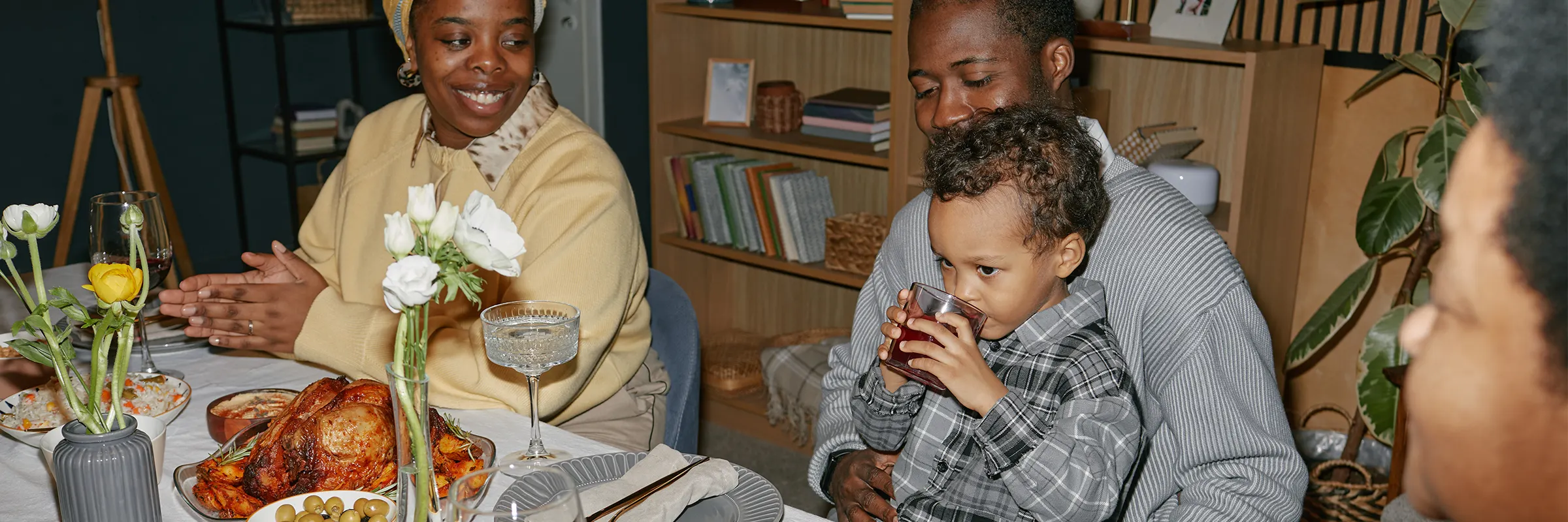 Multigenerational family sit at a dining room table having dinner. 