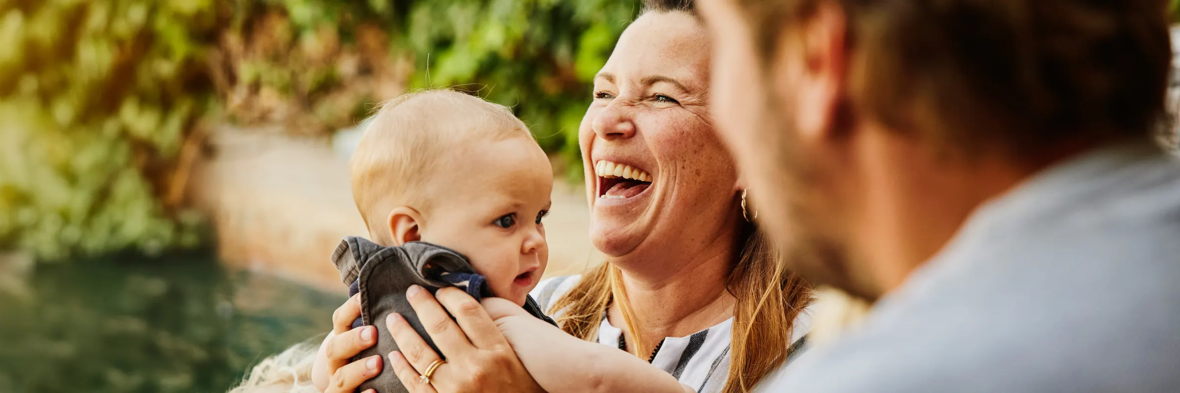 person holding toddler while laughing with family at tropical villa during vacation.