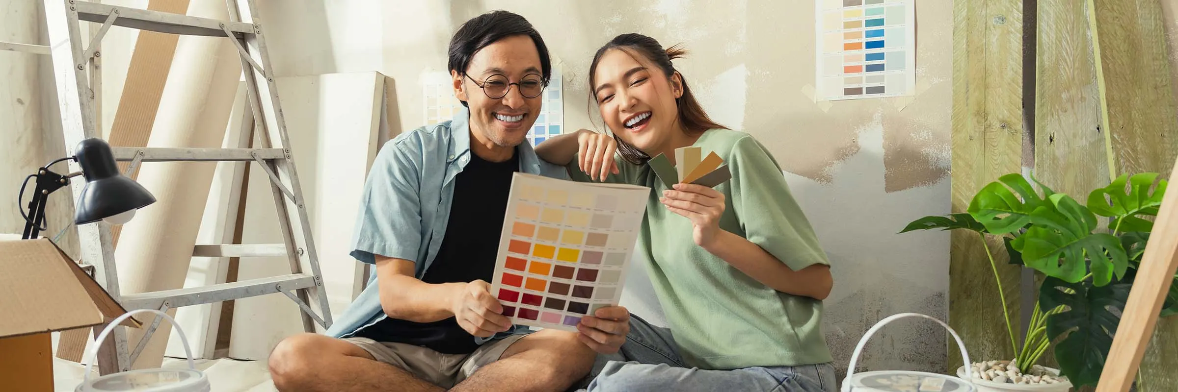 Happy man and woman sit on the floor and look at paint colors for their new home.