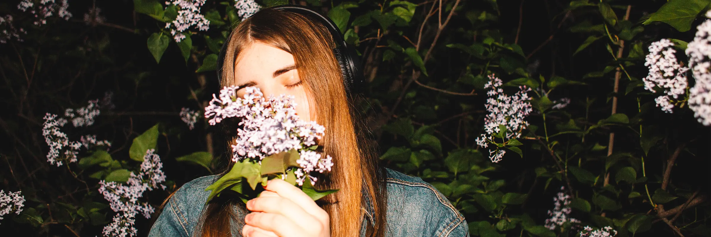 Young woman listening to music and smelling flowers
