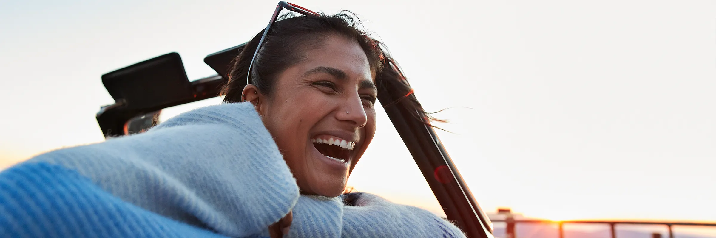 A person in a convertible laughs in the wind
