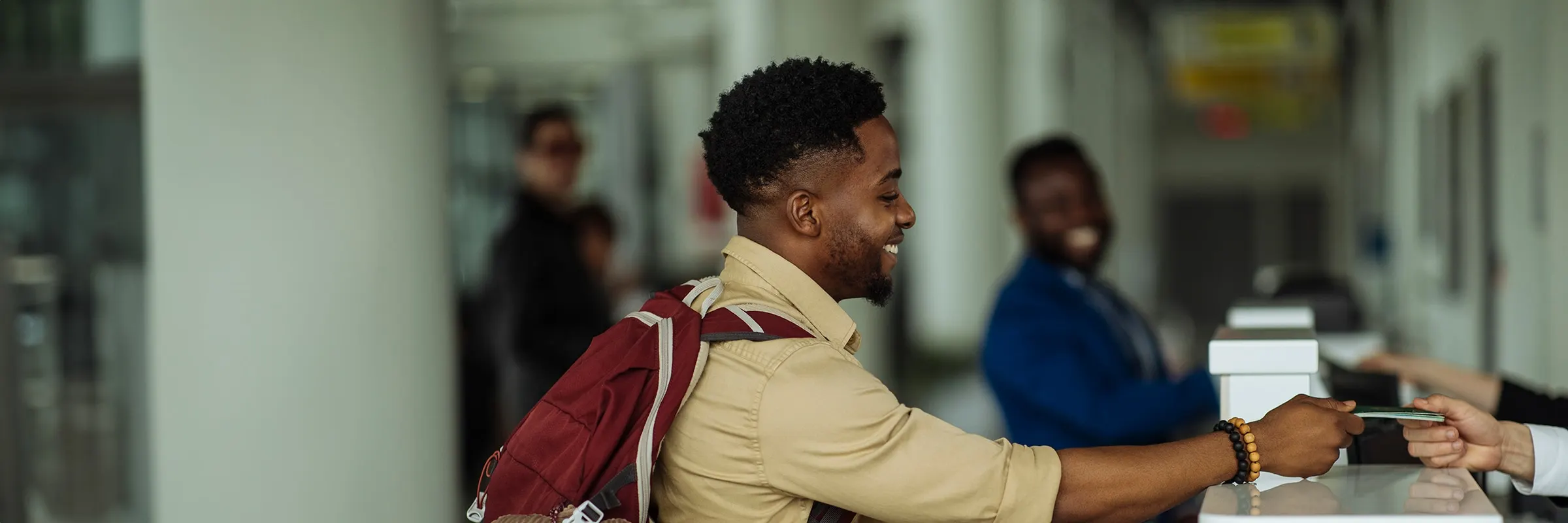 Side view of a young man standing in front of the airport counter