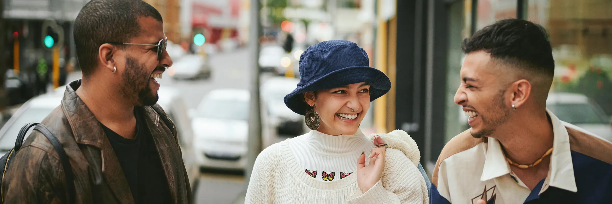 Three friends laugh together on the street.