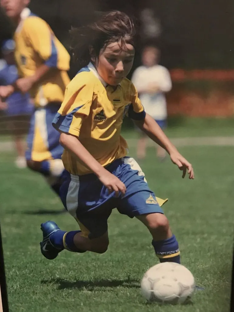 Young Brandt Bronico runs and dribbles a soccer ball on the field