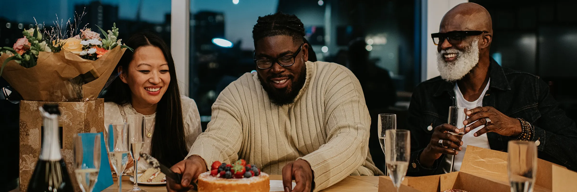 Coworkers hold a celebration at the office and one man reaches for a cake.