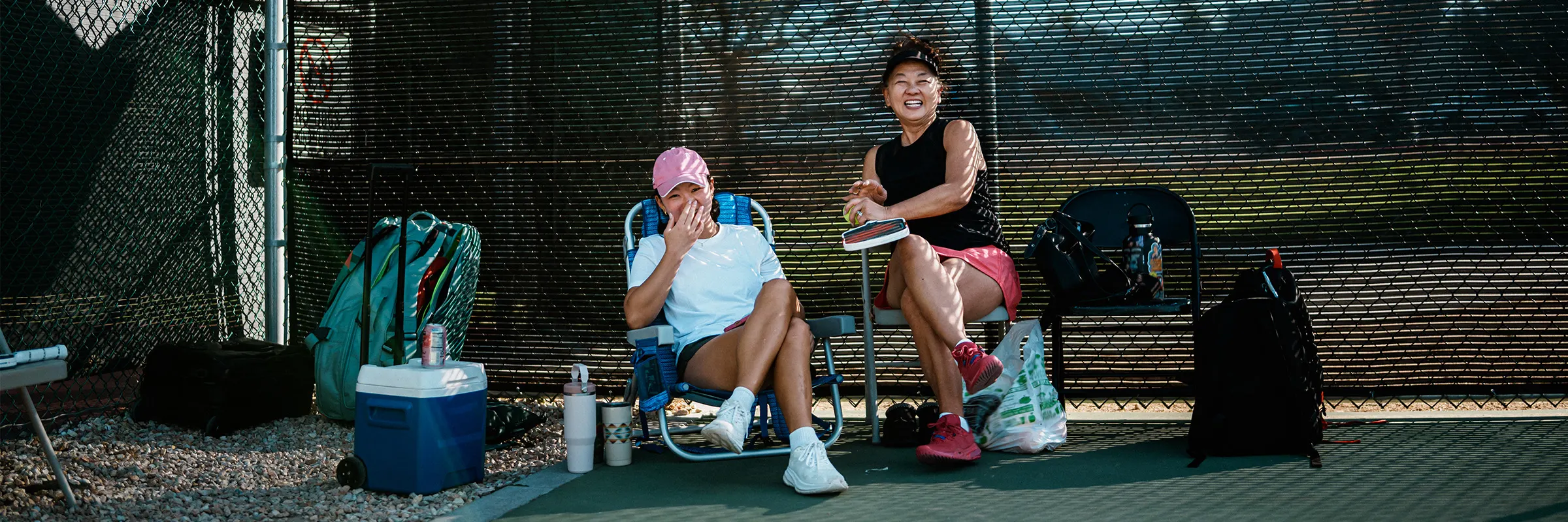 Mother and daughter take a break from playing pickleball and laughing together.