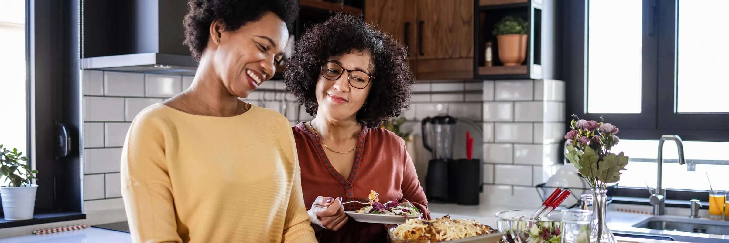 A couple at the kitchen counter eating and looking at a laptop