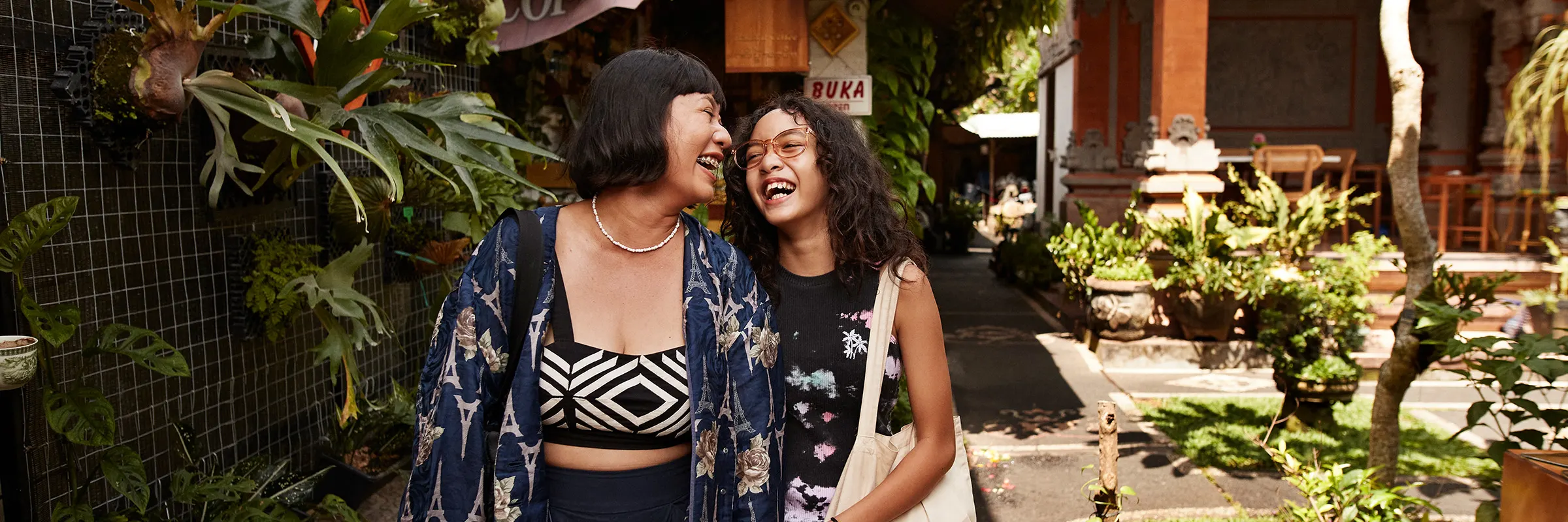 A mother and daughter walk through a courtyard garden while traveling abroad.