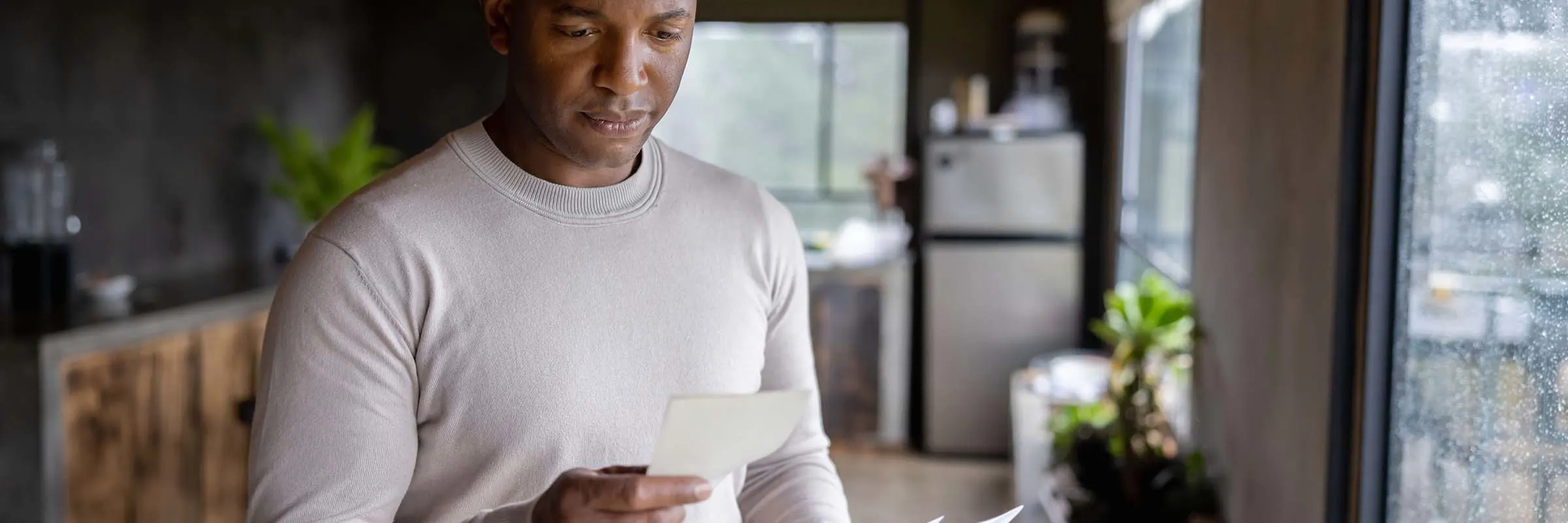 Man at home reading a letter in the mail and looking worried