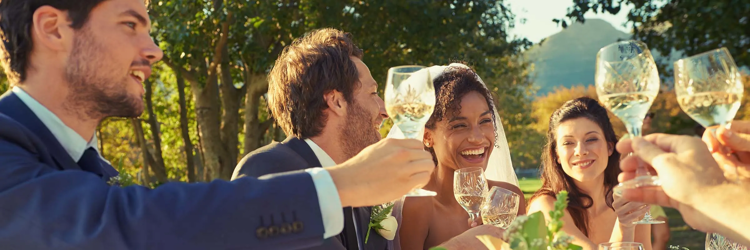 Bride and groom laughing as their wedding party toasts with champagne