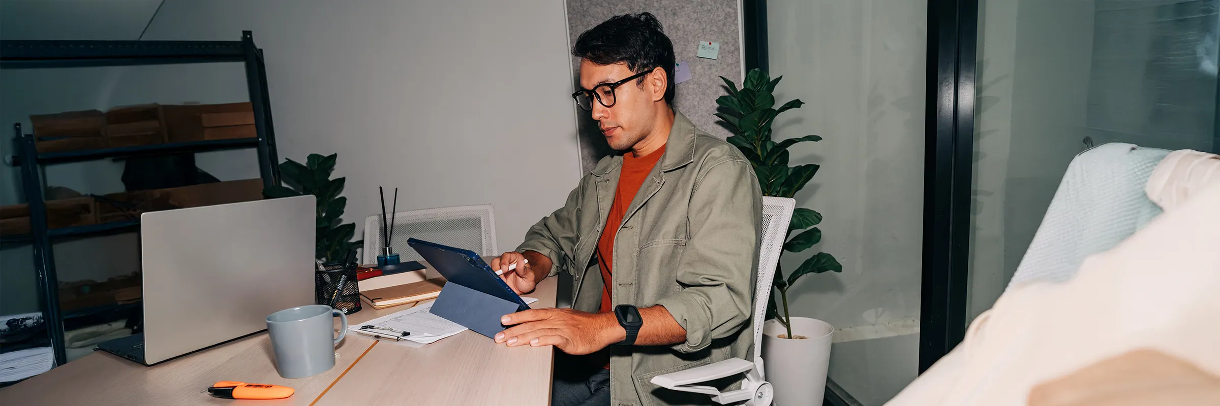 Professional in green jacket concentrating on tablet during office task