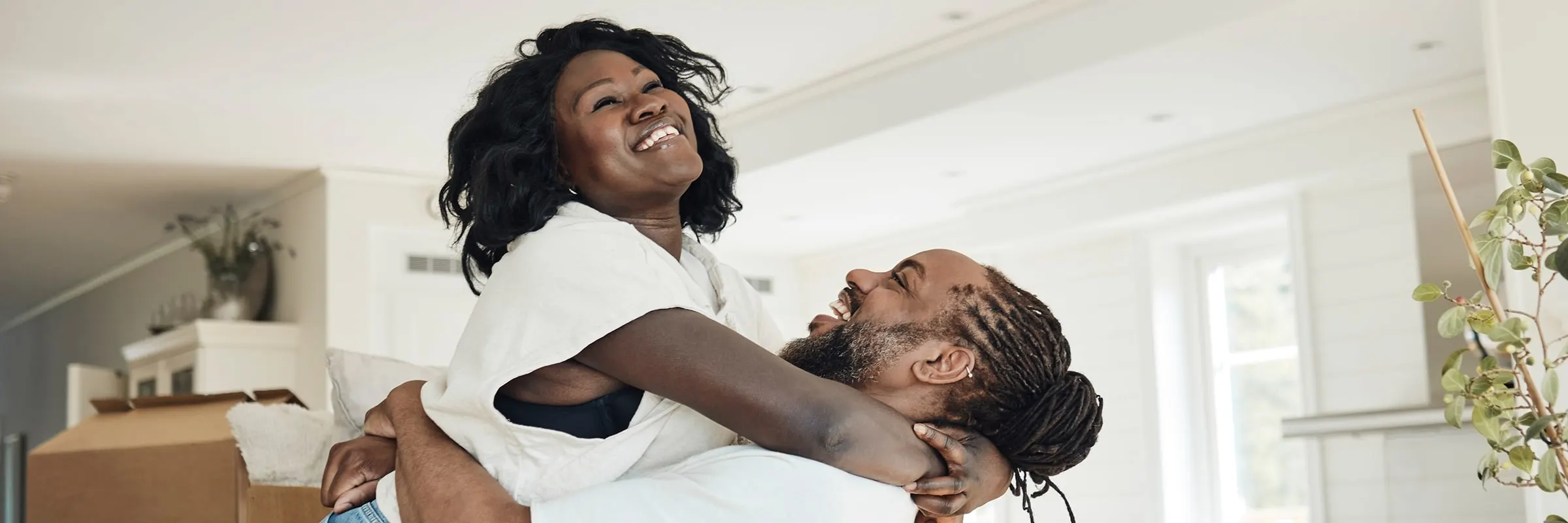  A man lifts a woman into his arms to celebrate moving into their first home together.