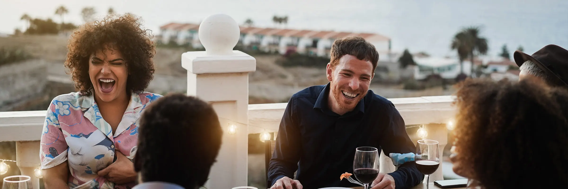 Friends enjoy a meal around an outdoor table.