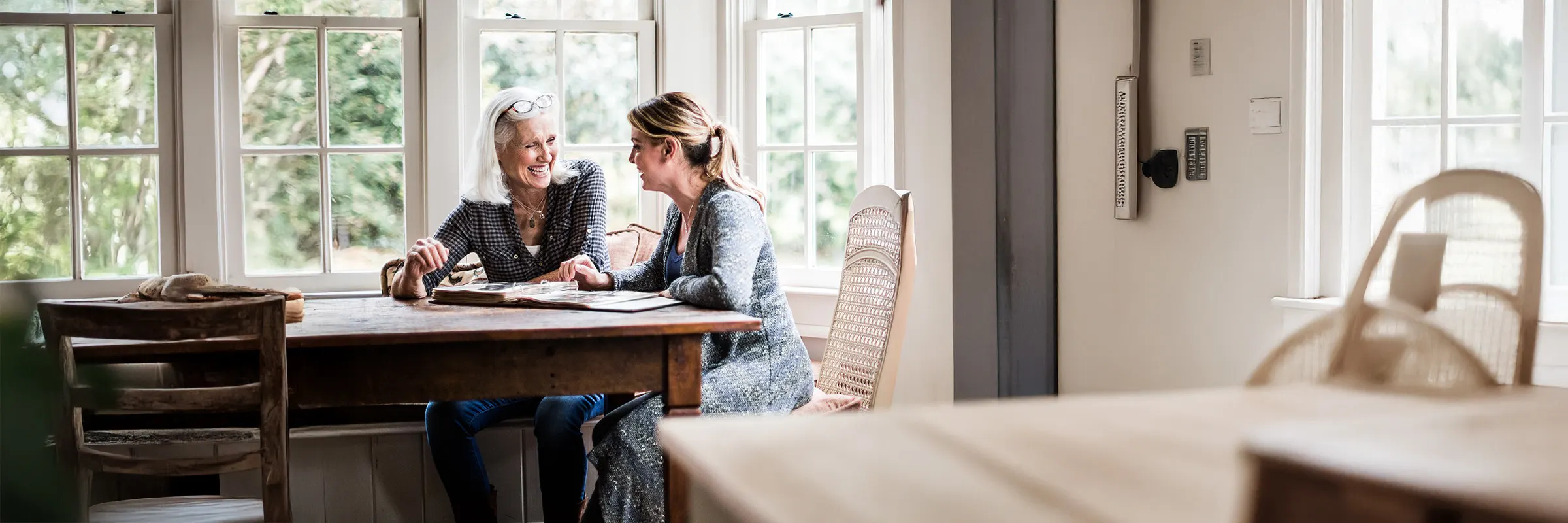 A younger adult looks through photos with an older adult while they both smile
