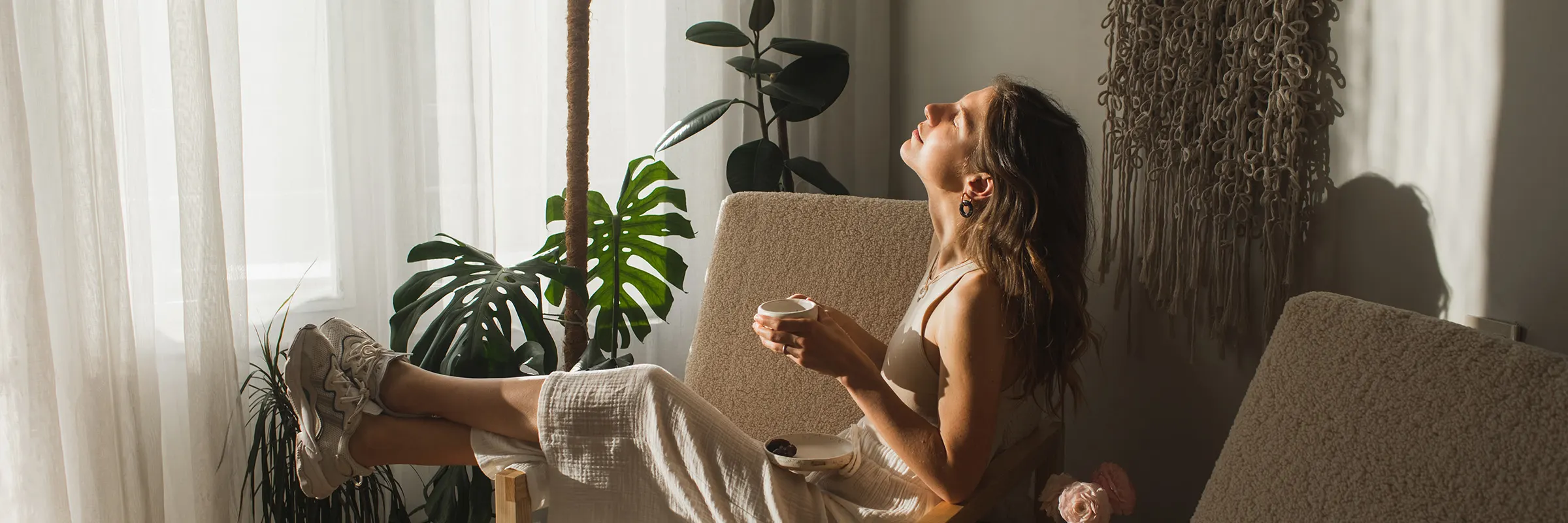 A woman relaxes in her chair while sipping coffee and enjoying the morning light.
