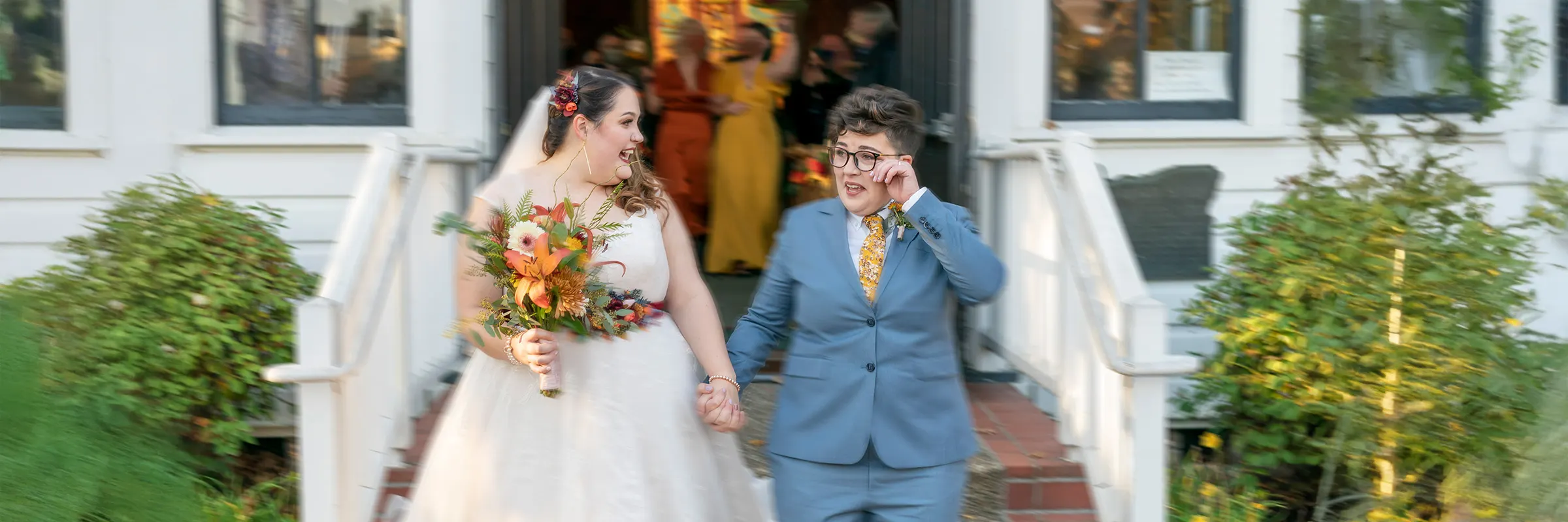 A young couple holds hands and walks out of a church after their wedding ceremony