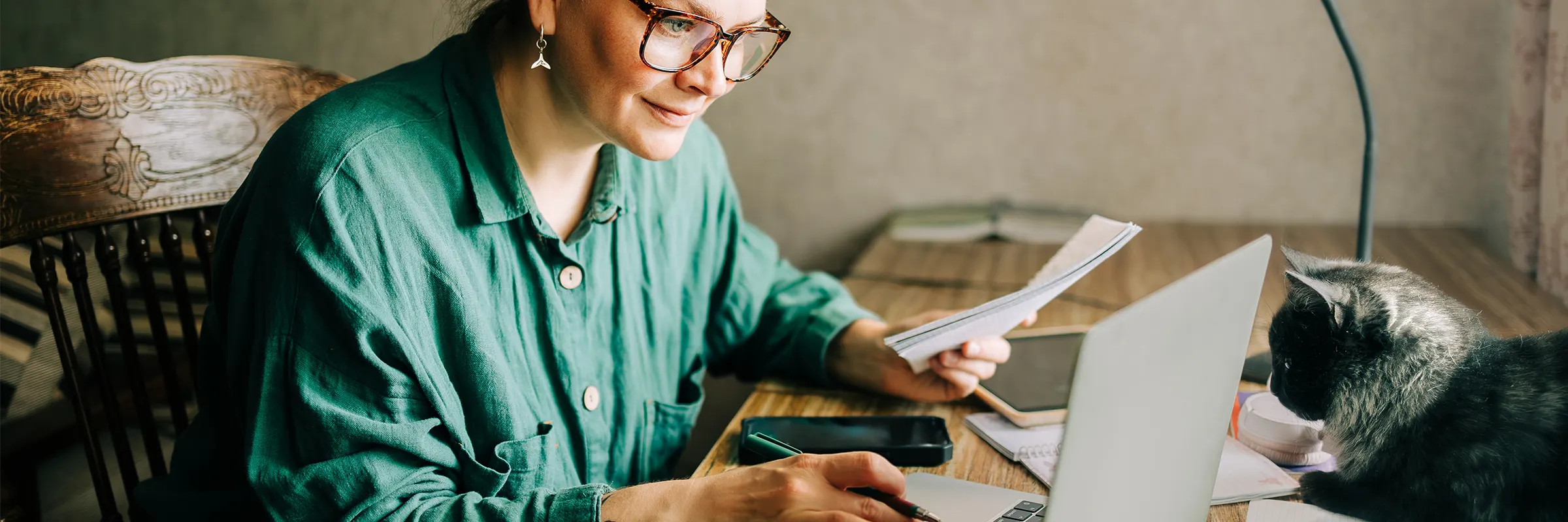  Woman sitting at a desk taking notes while looking at a computer. 
