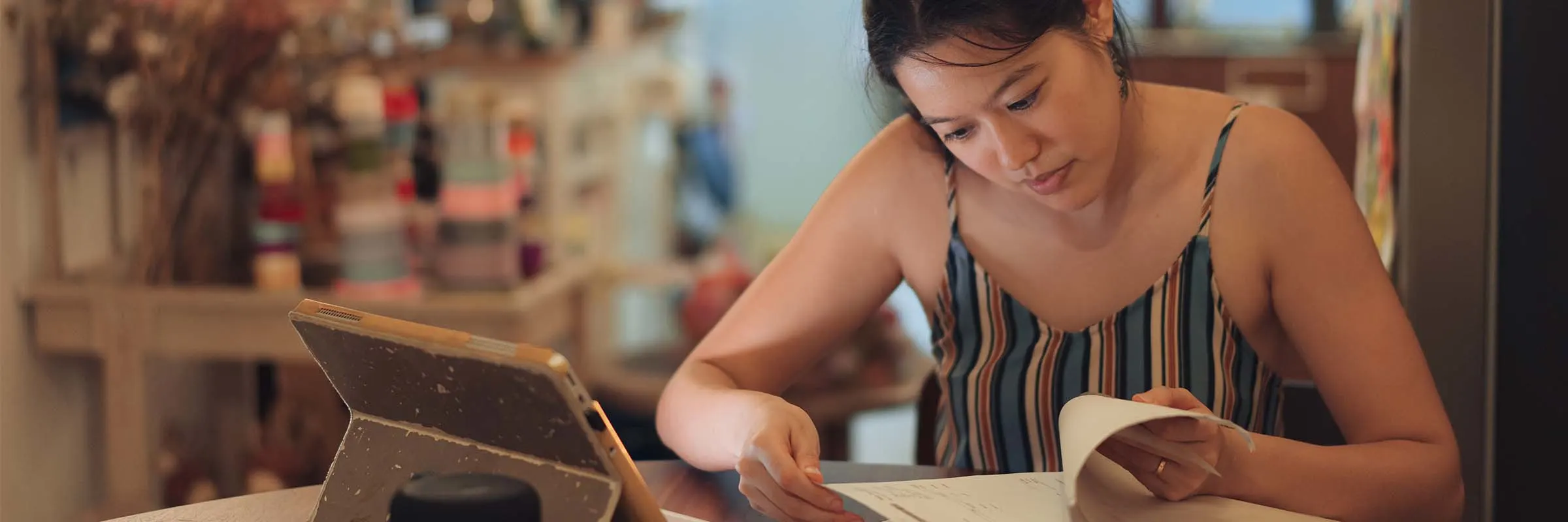Woman studying at a table with a tablet and papers
