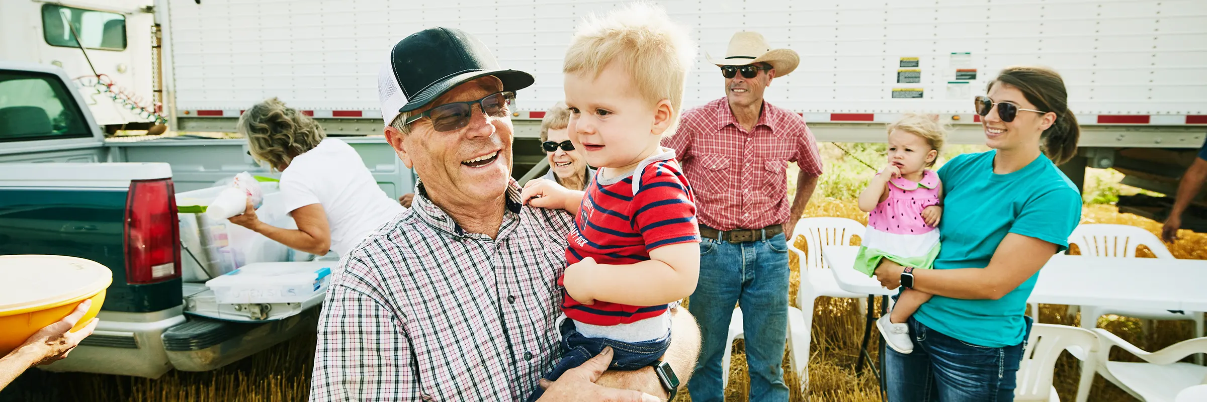 Father holding a child outside at a family gathering. 