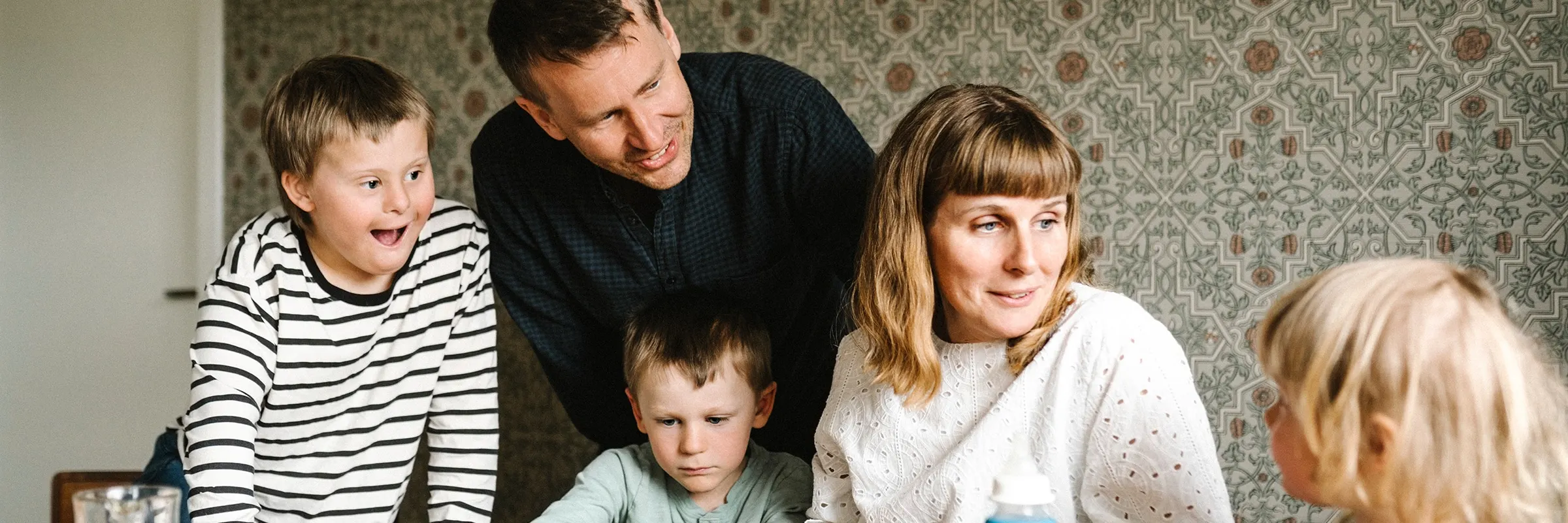  Smiling parents are gathered around a table with their three children.