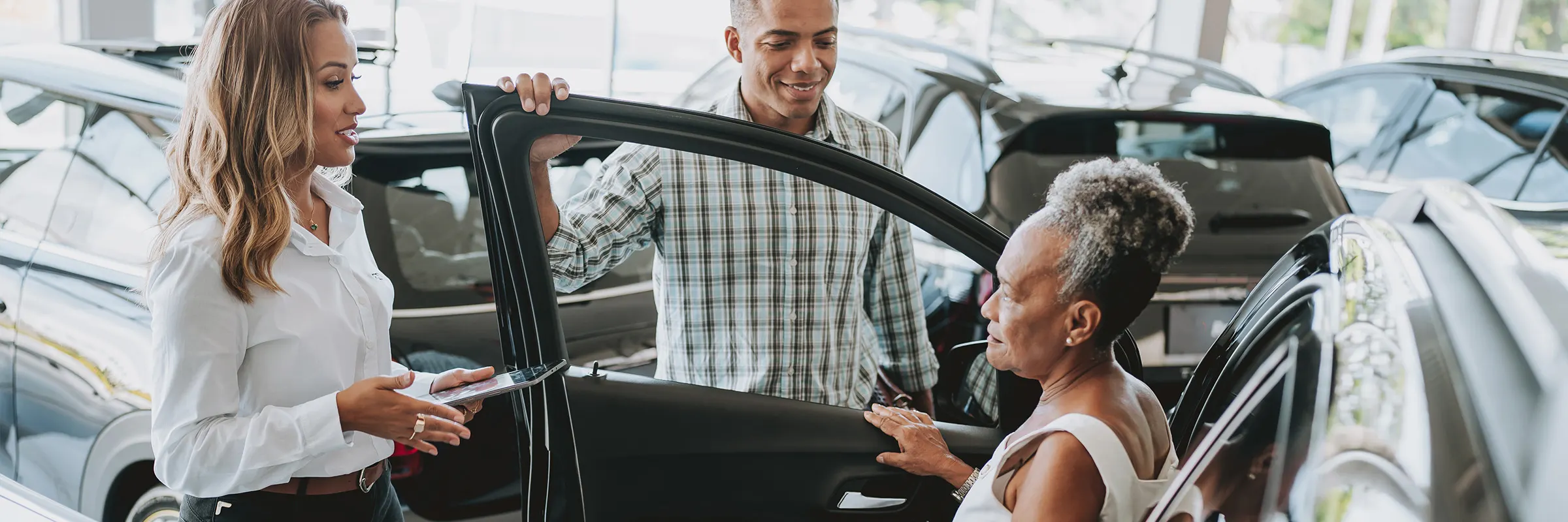 Mother and adult son purchasing a car in a showroom with a dealer.