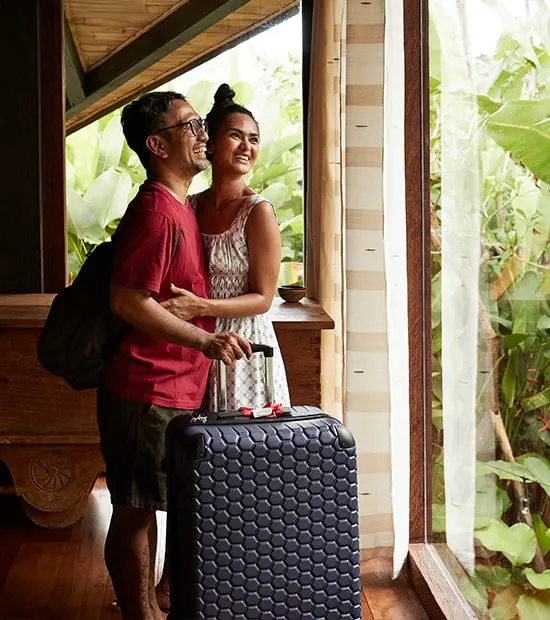 Couple smiling while looking out the window of their hotel room.