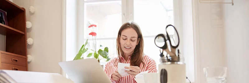 A woman happily budgeting while sitting at a desk.