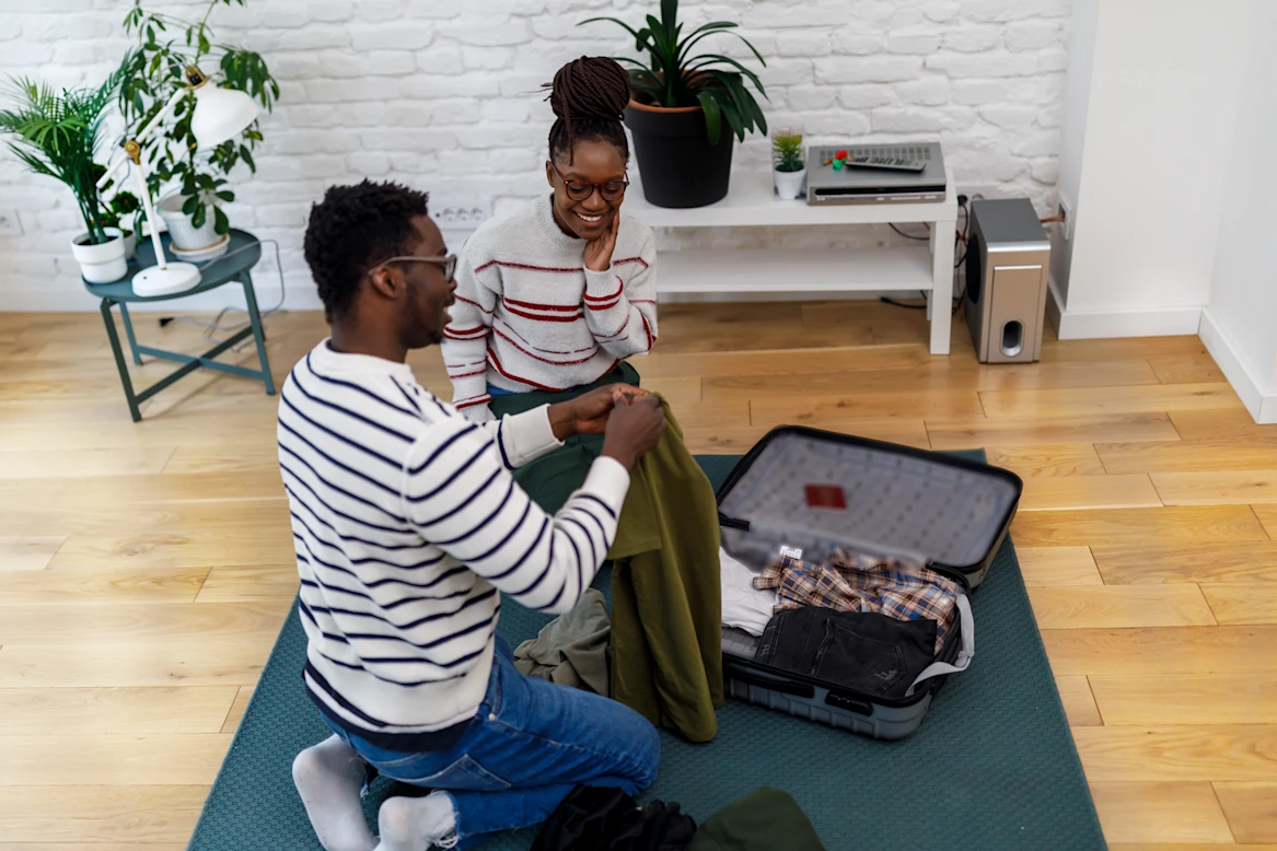 A couple sits on the floor together while packing for their trip.