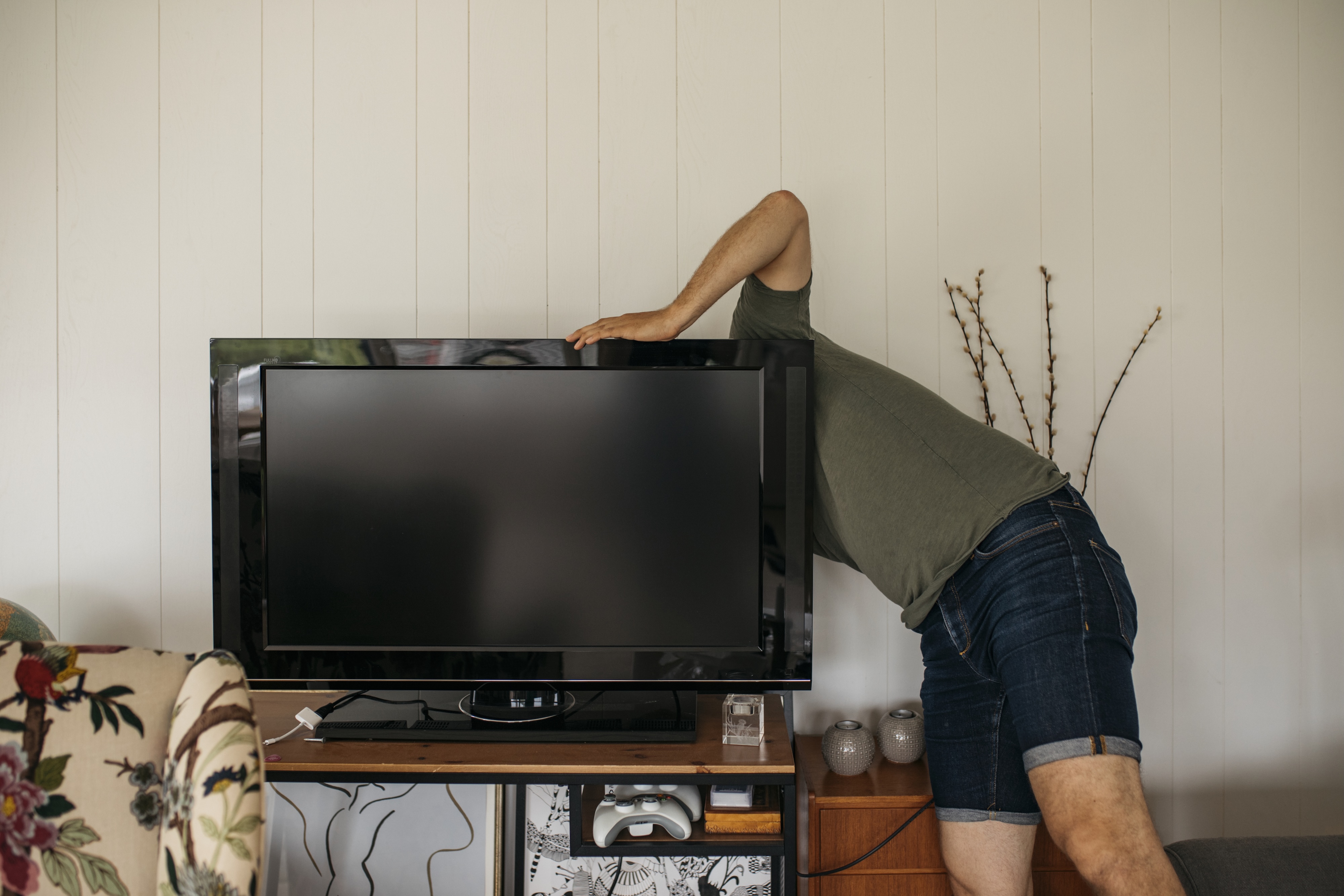 A person reaching behind a TV to install it