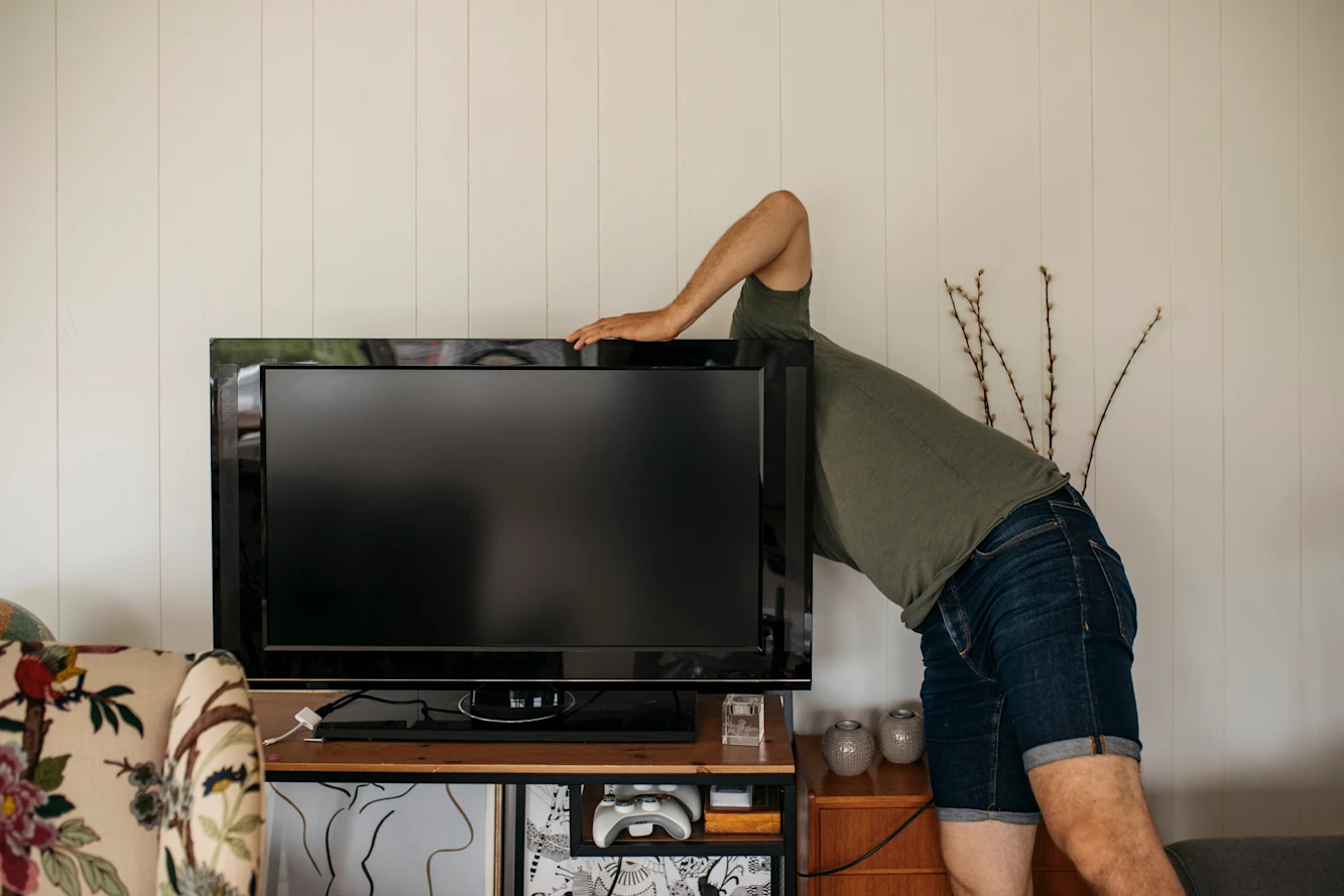 A person reaching behind a TV to install it