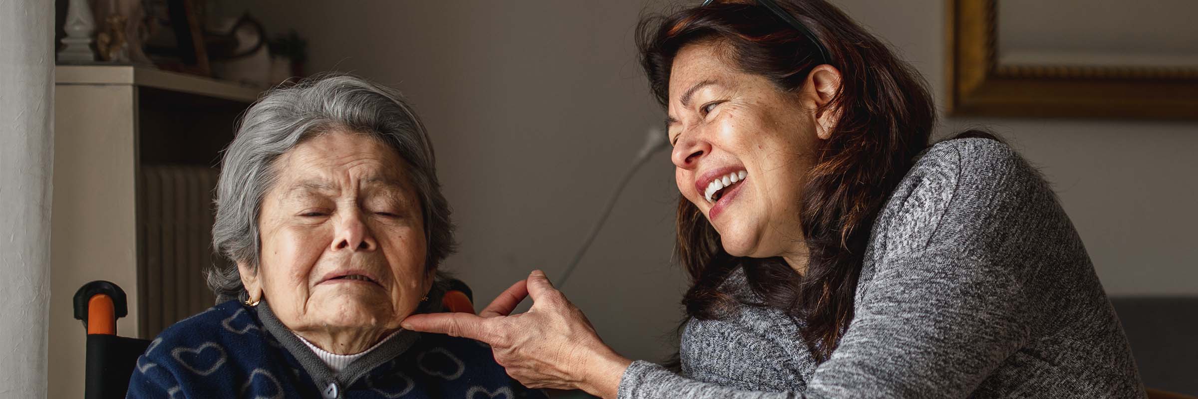 A woman looking ahead while embracing her mother.