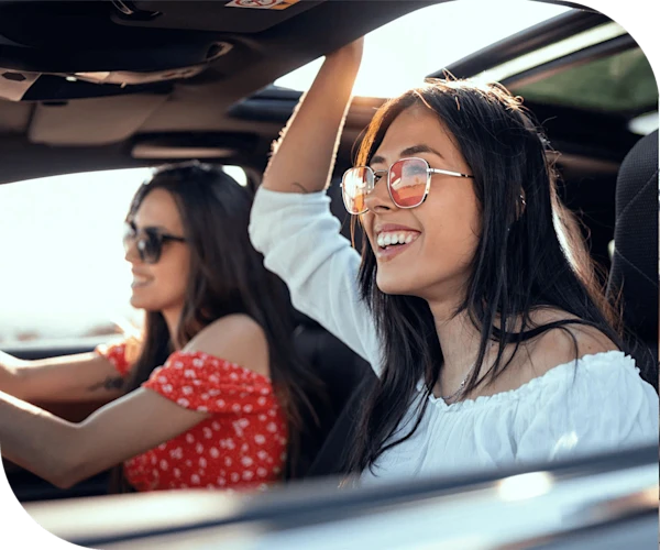 two people wearing sunglasses enjoying a car ride with the windows open on a sunny day