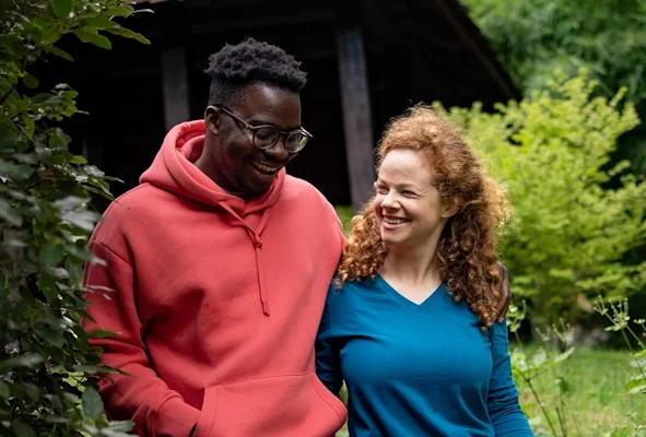 Happy couple walks through the wooded yard behind their house.