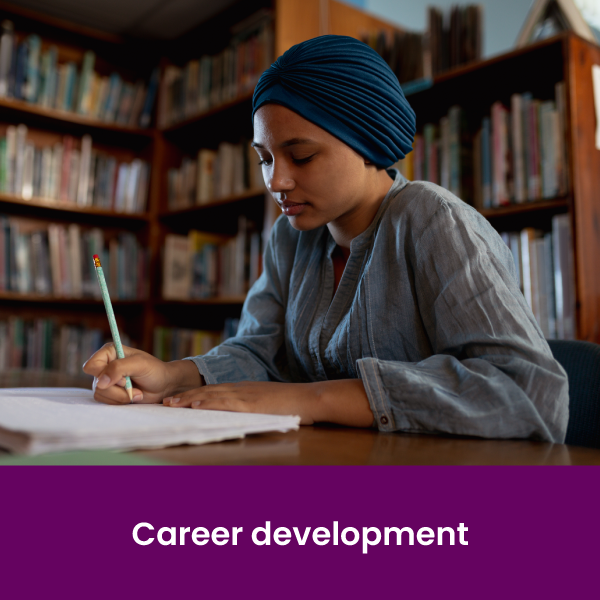 a woman sitting at a desk in a library holding a pencil and writing in a notebook