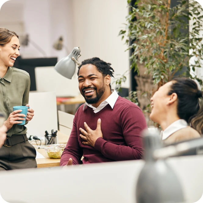 Two men and a woman chatting and laughing with each other in an office.