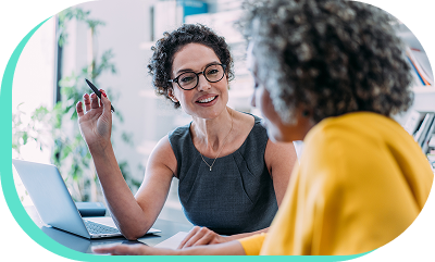 A smiling dealership employee sitting with a customer looking over information.