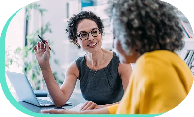 A smiling dealership employee sitting with a customer looking over information.