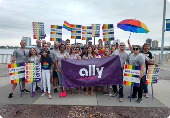 a group of volunteers celebrating pride while holding an Ally do it right banner
