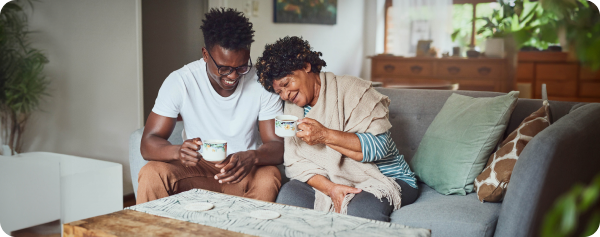 A grandmother and her grandson enjoying a cup of coffee together at home.