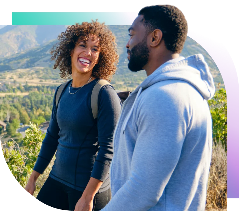 A smiling couple hikes in the mountains.