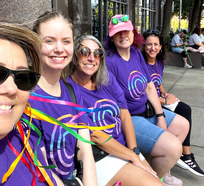 A smiling group of Ally Pride attendees sit together