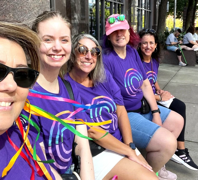A smiling group of Ally Pride attendees sit together