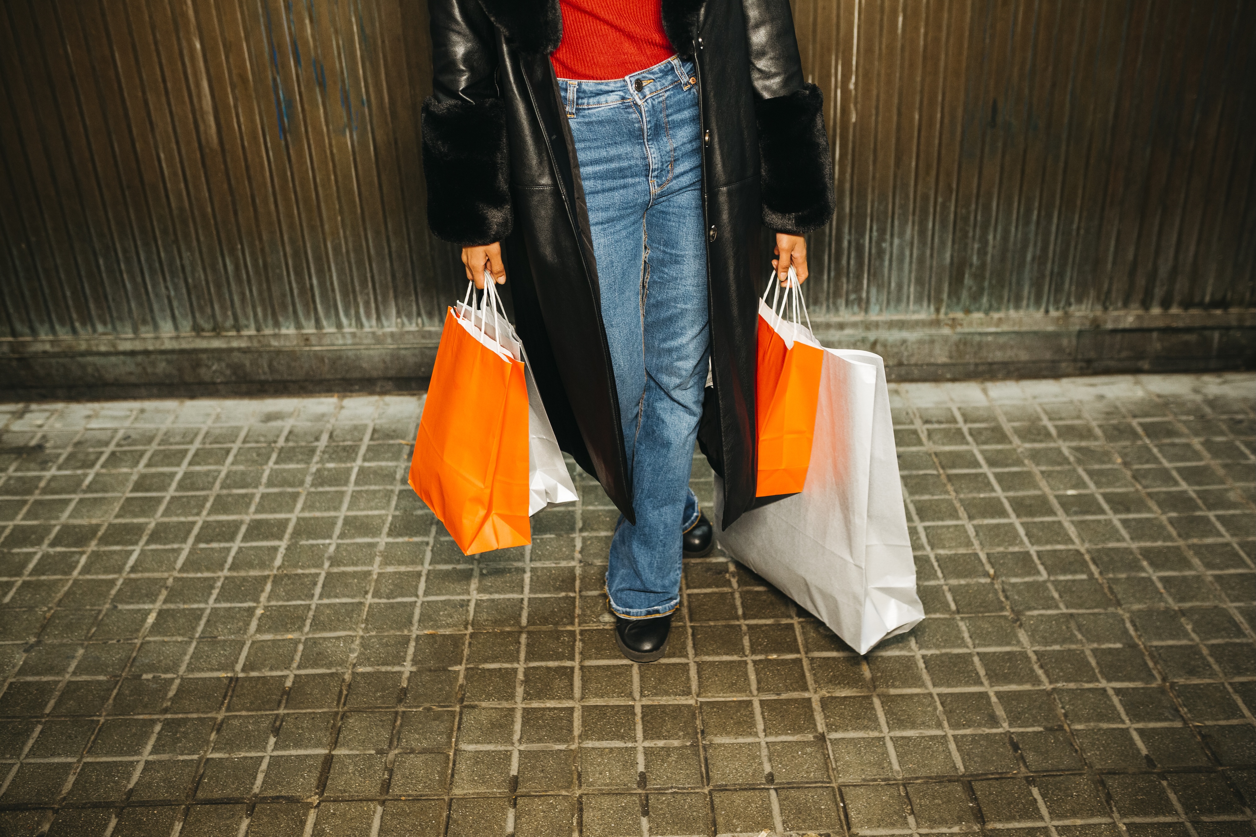 Person facing camera holding multiple shopping bags