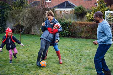 Family of four plays soccer in the backyard